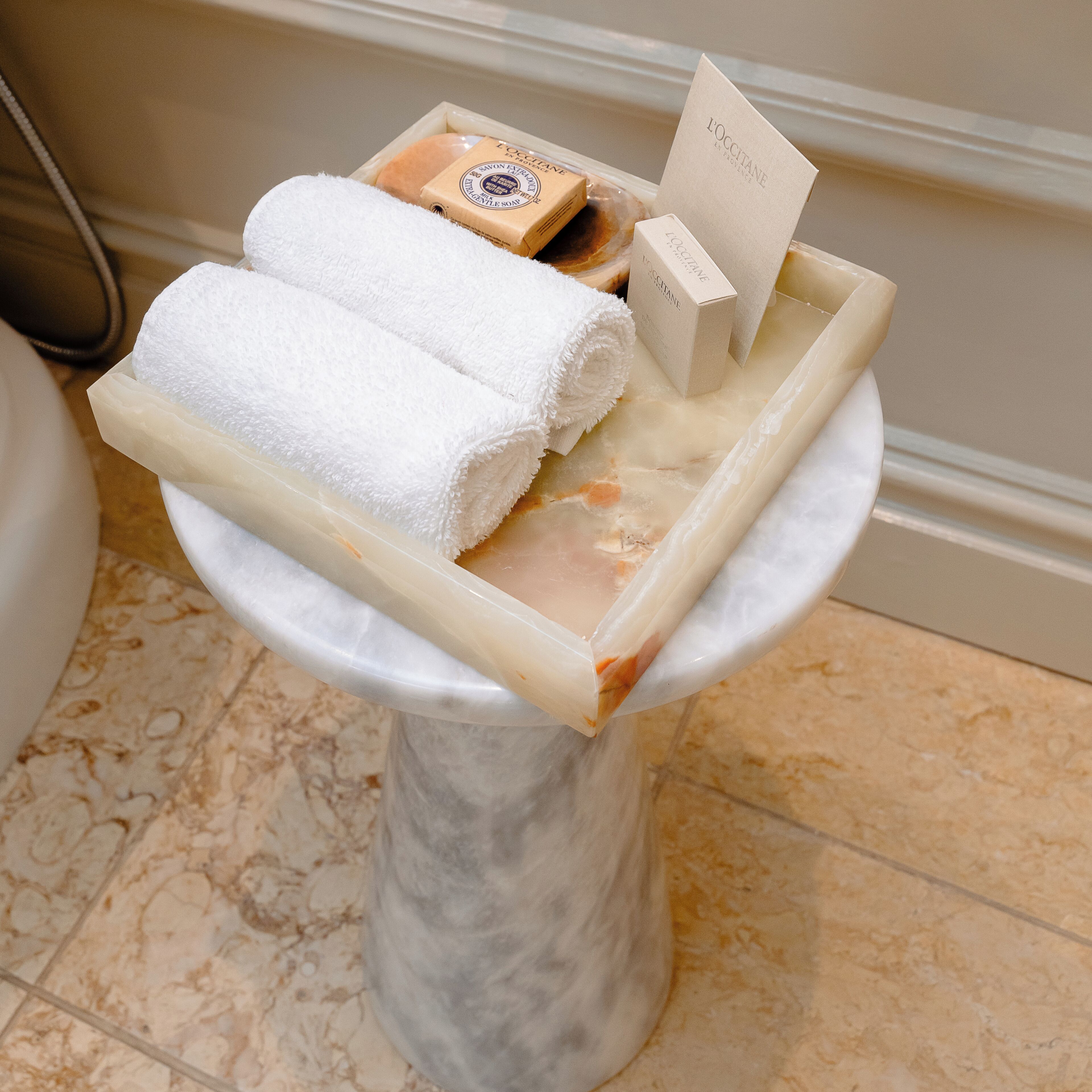 Un bany amb un lavabo de pedestal de marbre i productes de tocador.
