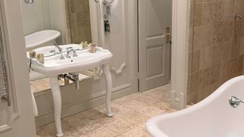 A bathroom with a white pedestal sink, a large bathtub, and a shower area.