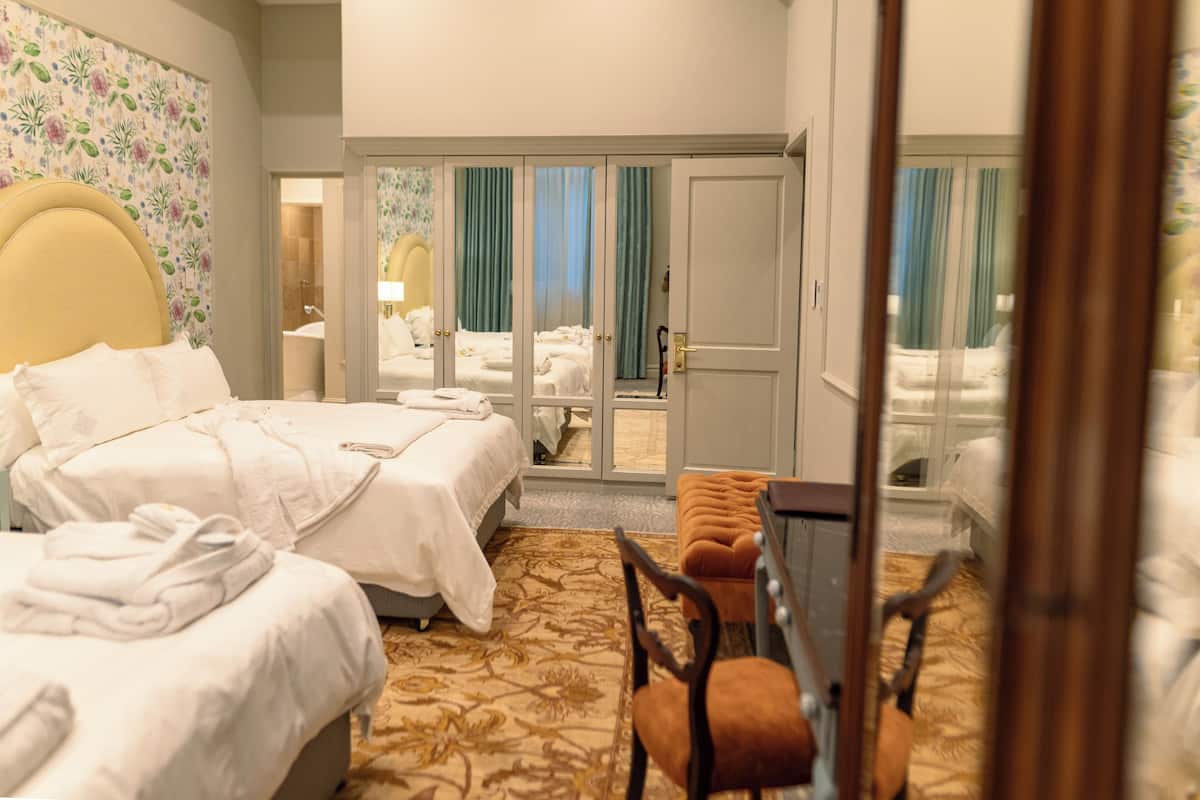 Ein Hotelzimmer mit zwei Betten, einer Sitzecke und Blick durch eine Glastür.