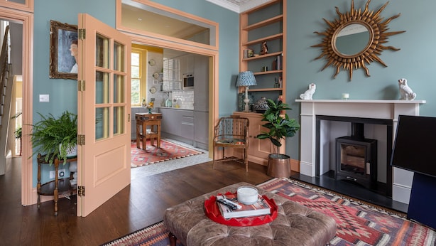 Een woonkamer met een open haard, een grote spiegel en een gezellige zithoek.
