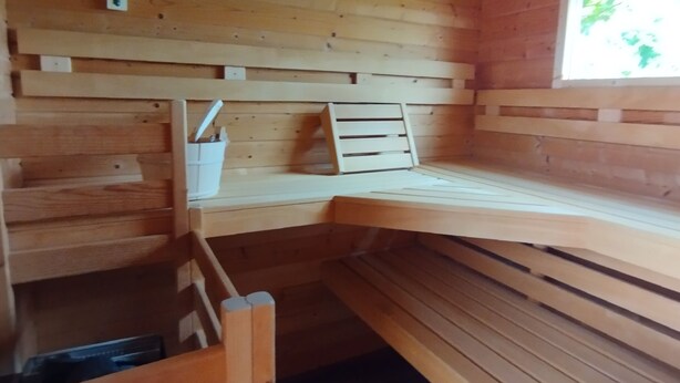 A wooden cabin interior with a built-in bench, a small window, and a wall-mounted shelf.