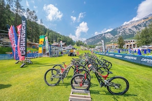 Een mountainbike evenement met meerdere fietsen geparkeerd op een grasveld, omringd door tenten en vlaggen.