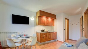 Een kleine woonruimte met een kitchenette, een eethoek en een bank.