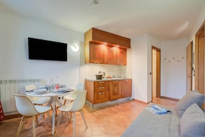 Een kleine woonruimte met een kitchenette, een eethoek en een bank.