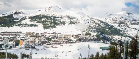 A snow-covered mountain town with buildings, ski slopes, and a lake.
