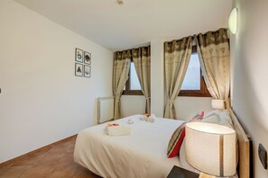 Een hotelkamer met een bed, een bedlamp, een raam met gordijnen en een radiator.