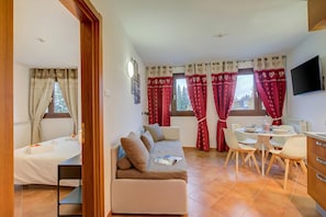 Une pièce comprenant un canapé, une table à manger avec des chaises, un téléviseur et un lit.