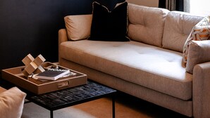A modern living room with a beige sofa, a black coffee table, and a flat-screen TV mounted on the wall. - New Holgate (York)