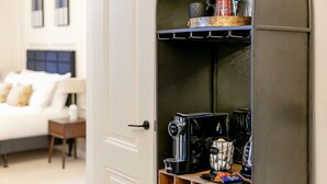 A hotel room with a bed, a nightstand, a coffee machine, and a shelf with various items. - New Holgate (York)