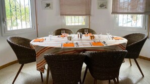 A dining area with a round table set for four, surrounded by wicker chairs. - SAONA VILLAS (VN LARA): villa 8 people, private pool, wifi (Les Tres Cales)
