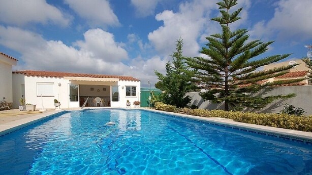A swimming pool with a clear blue water surface, a white building with a red-tiled roof, and a large pine tree in the background. - SAONA VILLAS (VN LARA): villa 8 people, private pool, wifi (Les Tres Cales)