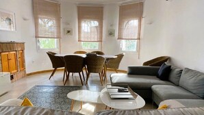 A living room with a grey sofa, a round coffee table, a dining table with chairs, and a grey couch. - SAONA VILLAS (VN LARA): villa 8 people, private pool, wifi (Les Tres Cales)