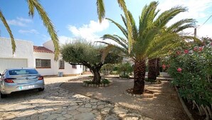 A paved driveway leading to a white building with a car parked on the left. - SAONA VILLAS (VN LARA): villa 8 people, private pool, wifi (Les Tres Cales)