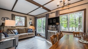 A modern living room with a wooden dining table, a sofa, and a TV. - Red Barn | Waterfront | Private | Tobermory | A-Frame | Pet Friendly (Tobermory)