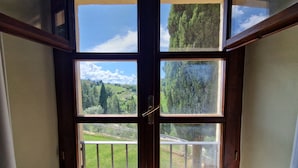 Habitación de esquina con un amplio ventanal que da a un paisaje verde y un cielo despejado.