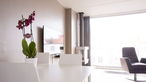 A modern living room with a white table, a sofa, and a potted orchid. - Klostergaarden leilighetshotell (Stavanger)