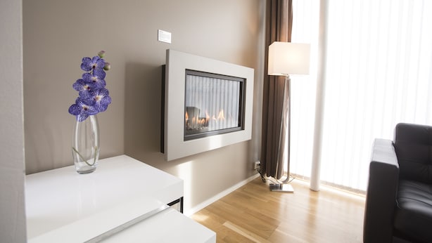A modern living room with a fireplace, a vase of flowers, and a lamp. - Klostergaarden leilighetshotell (Stavanger)