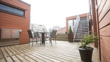 Enjoy outdoor dining or relaxation on the deck with a table and chairs, surrounded by a potted plant.