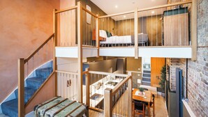 Ein Schlafzimmer im Loft-Stil mit Hochbett, Treppe, Essbereich und Küche.