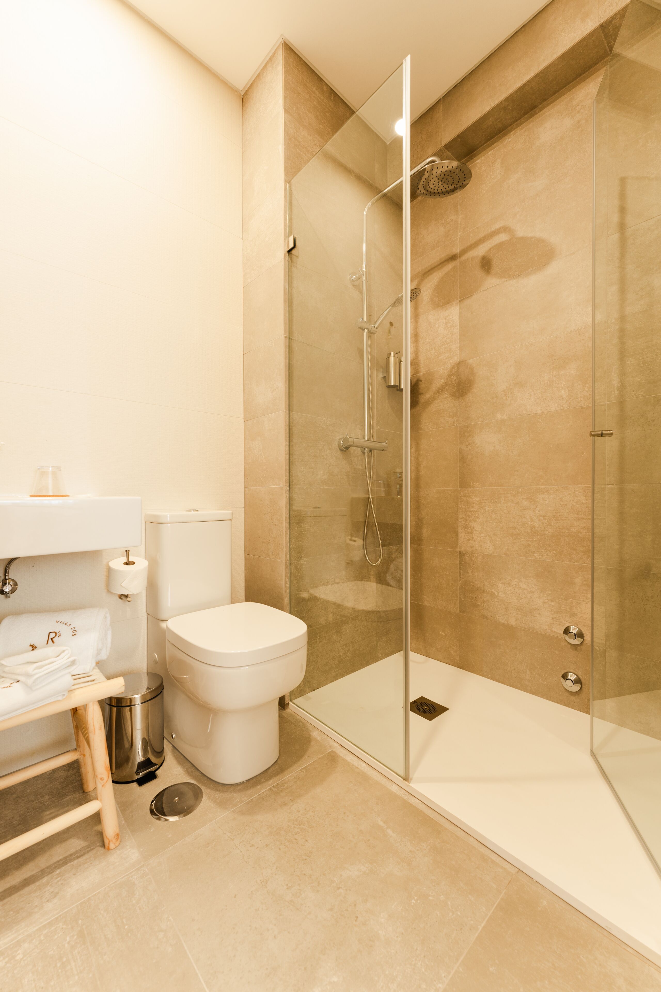 Une salle de bain moderne avec une douche à parois de verre, des toilettes et un lavabo équipé d’un porte-serviettes.