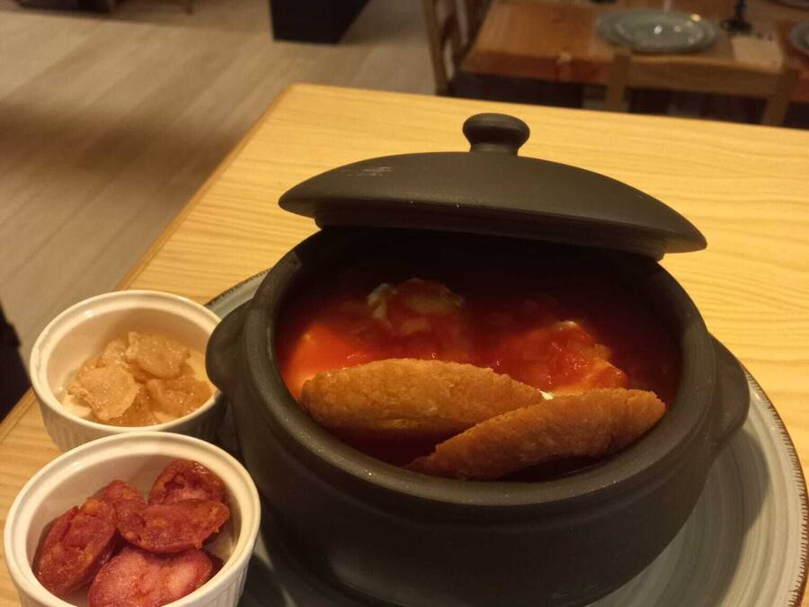 Ein Esstisch mit einem großen Topf Suppe und zwei kleinen Schalen Beilagen.