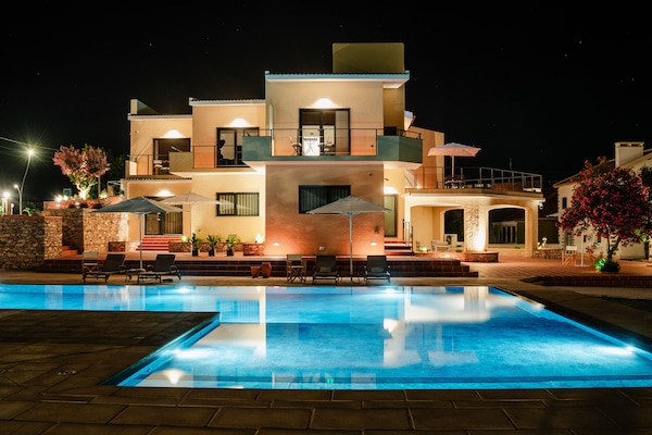 Una piscina al aire libre, sombrillas, sillones reclinables de piscina