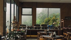A restaurant with large windows, wooden furniture, and a variety of kitchen equipment. - ARTOTEL Cabin Bromo (Ngadisari)