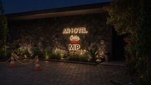 A stone wall with a neon sign for AR+TEL Cabin, indicating a property within the MIP. - ARTOTEL Cabin Bromo (Ngadisari)