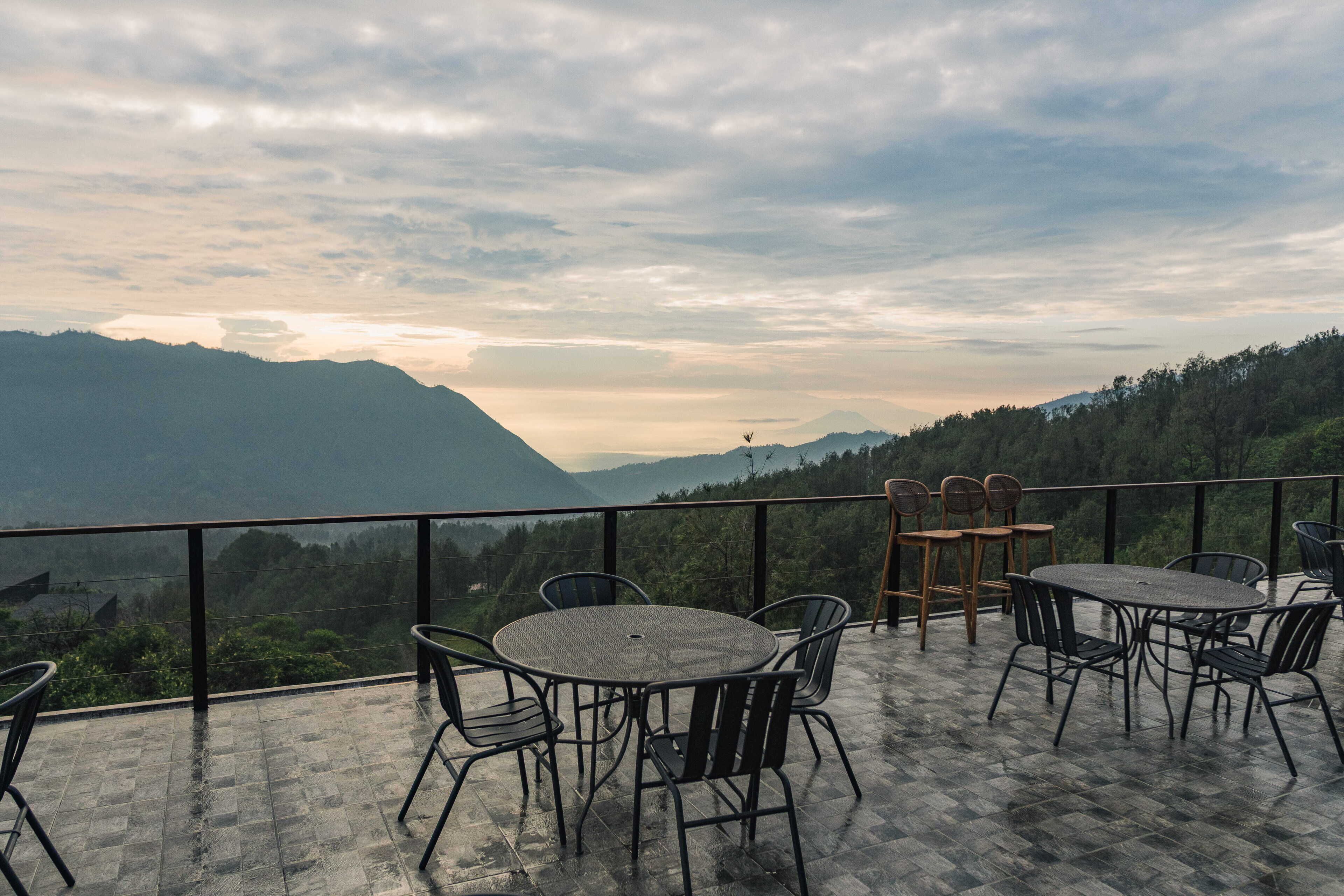 A terrace with a table and chairs, overlooking a mountainous landscape.