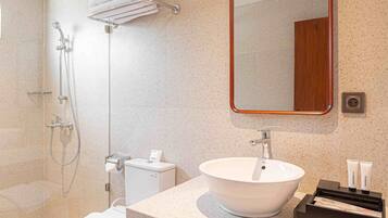 Ein modernes Badezimmer mit freistehender Toilette, einem Waschbecken mit Spiegel darüber und einer Duschkabine.