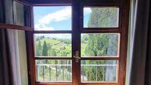 A room with a large window overlooking a green landscape. - Farmhouse Ai Massi ANNAMARIA (Guardistallo)