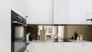 A modern kitchen with white cabinetry, a black oven, and a stainless steel countertop. - 3-BR Apartment in Prime Antwerp Location (Antwerpen)