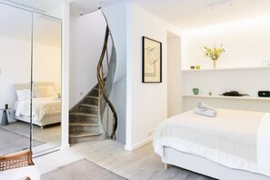 A modern bedroom with a large bed, a glass partition, a wooden staircase, and a minimalist decor. - 3-BR Apartment in Prime Antwerp Location (Antwerpen)