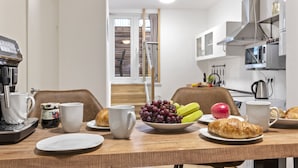 A breakfast table with croissants, grapes, an apple, and a coffee machine. - Old Town! Exclusive apartment with roof terrace for 6 people (3 rooms, 90 sqm) (Nürnberg)