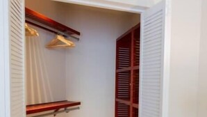 A walk-in closet with wooden shelves, a radiator, and a white door. - Dutch Caribbean Residence E (Aruba Beach Club)