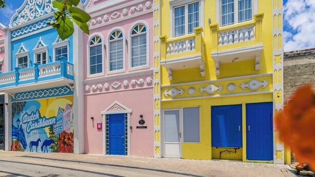 A colorful building with a blue door, a pink door, and a yellow door. - Dutch Caribbean Residence E (Aruba Beach Club)