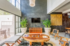 A modern interior with a round wooden table, seating, and potted plants.