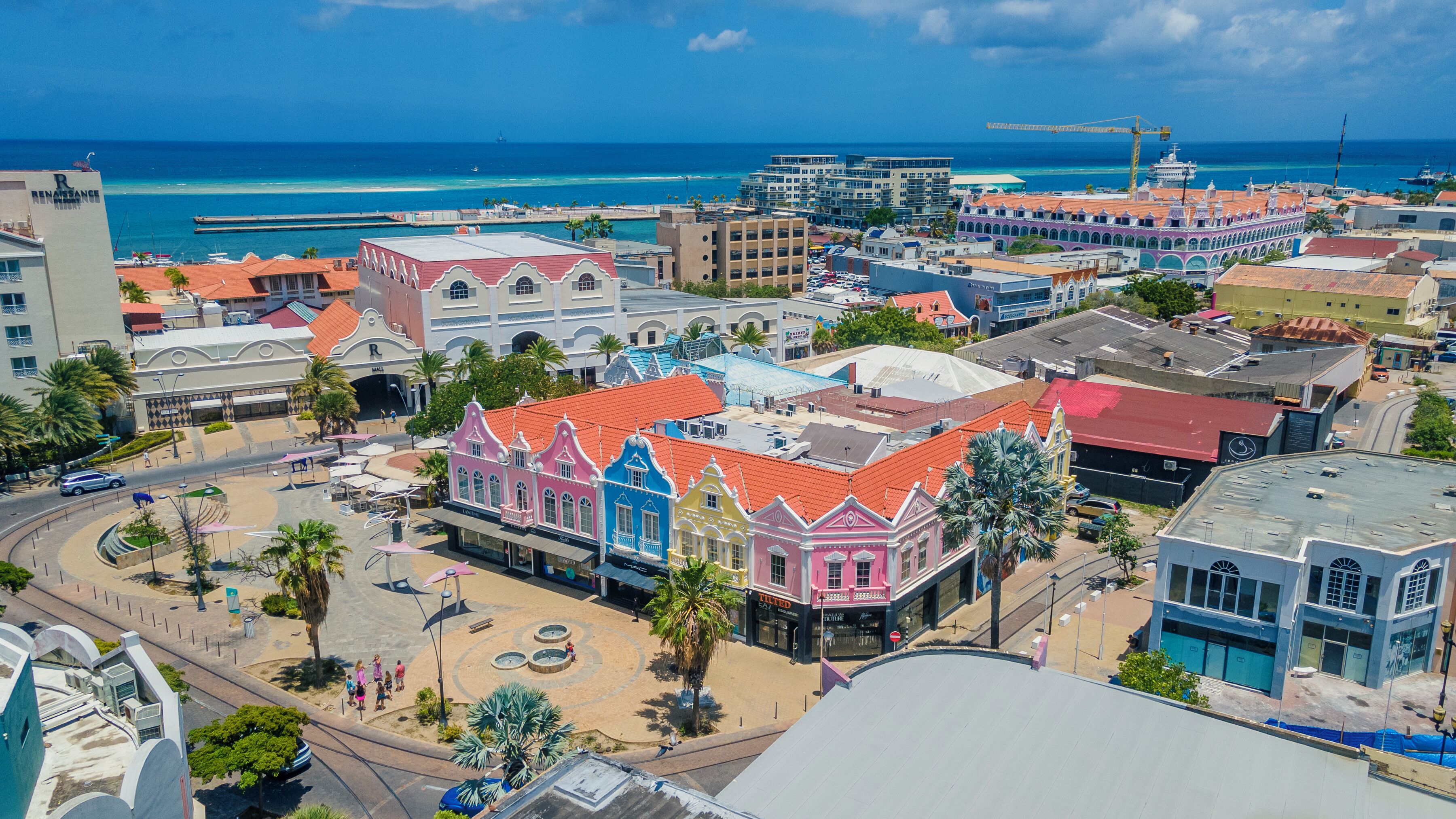 A coastal town with colorful buildings, a central plaza, and a view of the ocean.