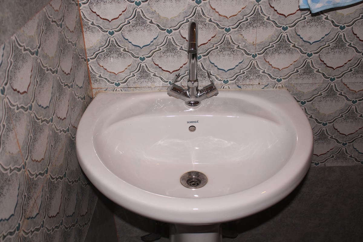 A white bathroom sink with a single faucet, set against a patterned tile backsplash.