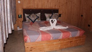 A wooden-paneled room with a bed featuring a geometric-patterned bedspread and decorative pillows. - Hotel Cloud Hills (Dharamshala)