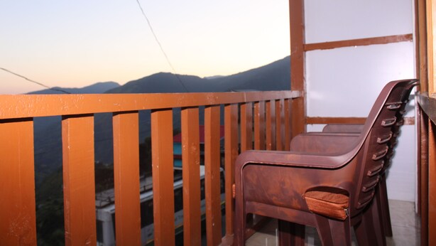 Un balcon avec une balustrade en bois et une chaise marron.