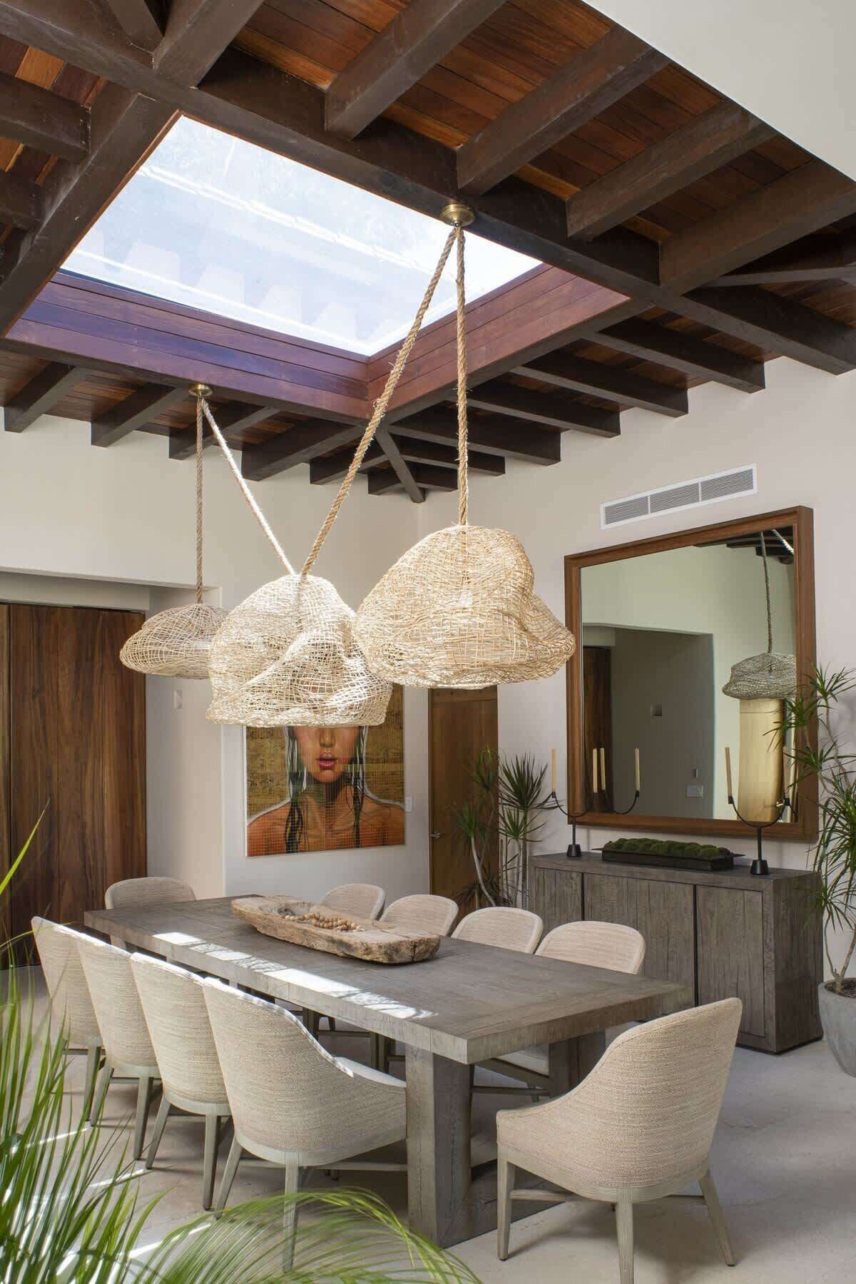 A dining area with a large table, six chairs, and three woven pendant lights.