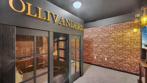 A hotel entrance with a brick wall and a sign reading "OLIVANDERS".