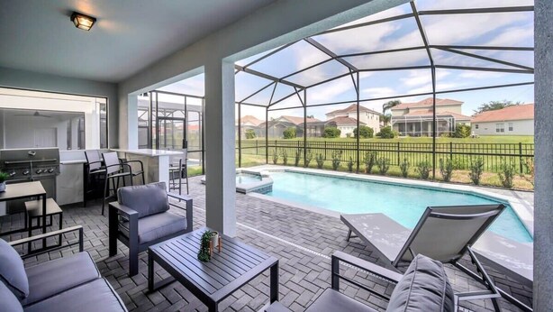 A covered outdoor area with a pool, seating, and a kitchen.