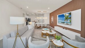 A modern living room with a sofa, armchairs, a coffee table, and a TV mounted on the wall.