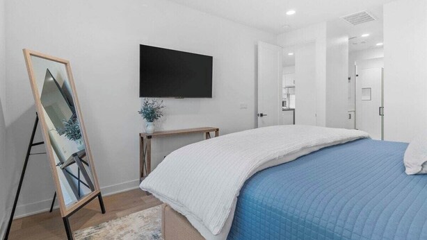 A bedroom with a bed, a flat-screen TV, a mirror, and a door leading to another room. - Desert Hideaway: 2BR/2BA, BBQ, FirePit, PGA West! (La Quinta)
