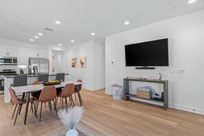 A modern kitchen with white cabinets and a dining area with a table and chairs.