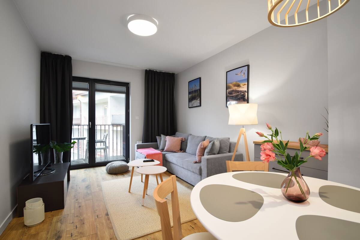 A modern living room with a sofa, a dining table, and a TV.