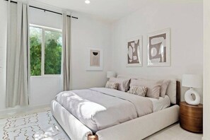 A bedroom with a bed, curtains, a window, and wall art.