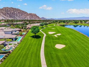 A golf course with a clear path, water hazards, and a mountain in the background. - Desert Chill: Pool & Spa at PGA West Stadium (La Quinta)